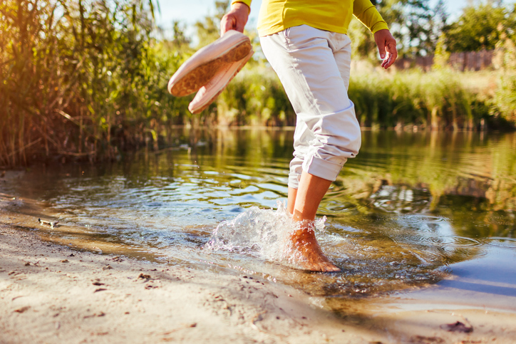 Middle-aged woman walking on river bank on autumn day. Senior lady having fun in the forest enjoying nature. Closeup